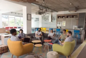 pessoas em uma conversa informal em uma área comum de coworking, transmitindo colaboração e bem-estar.
