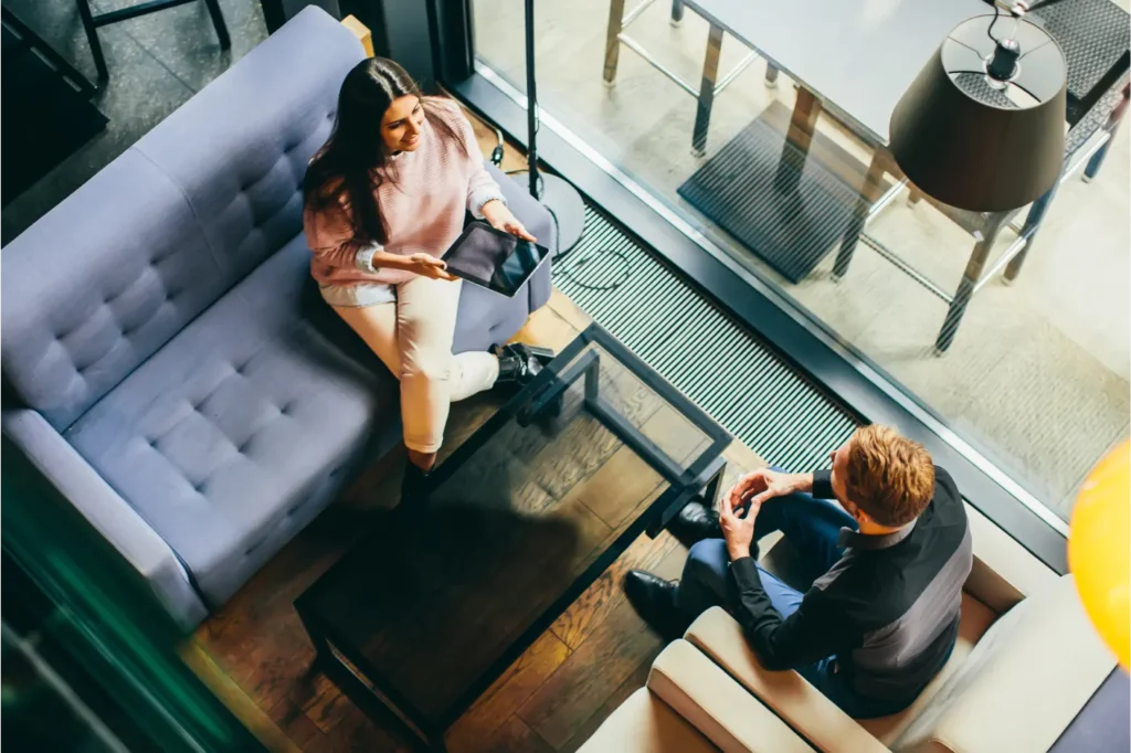 momento de conversa informal entre duas pessoas de empresas diferentes na área comum do coworking, sugerindo networking. 